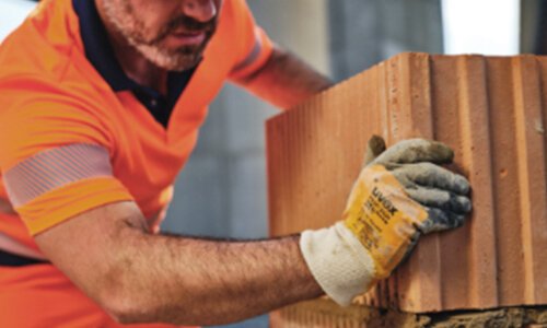 Bauarbeiter beim Mauerbau mit uvex Schutzhandschuh