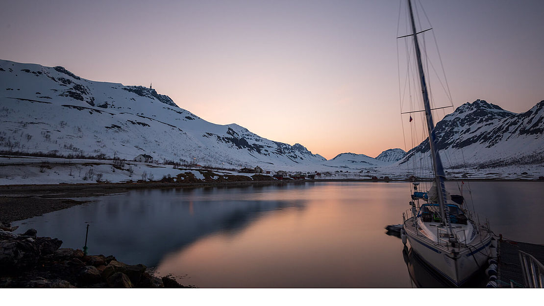 Sail and Summit – With the sailboat to the summit Sailboat in a snowy bay at sunset