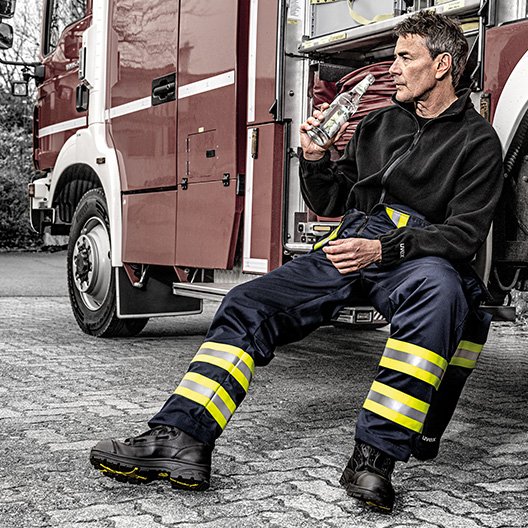 [Translate to French:] Feuerwehrmann in der Pause in uvex Schutzkleidung