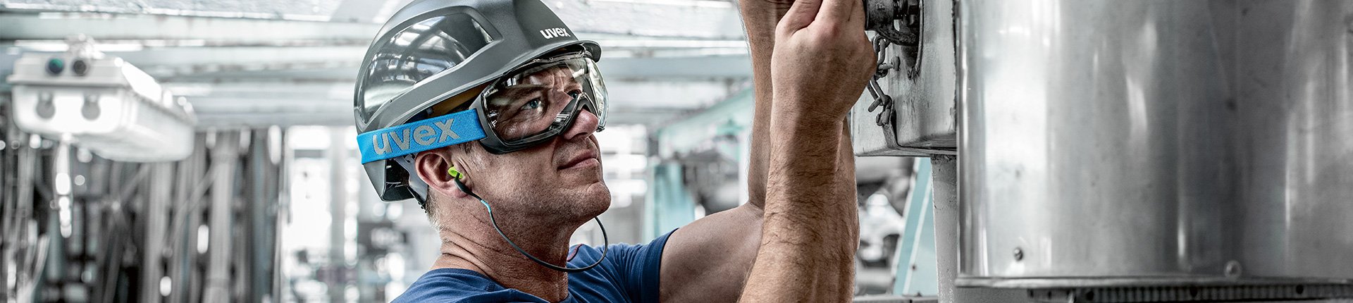 mężczyzna noszący szary hełm, gogle ochronne i zatyczki na pałąku