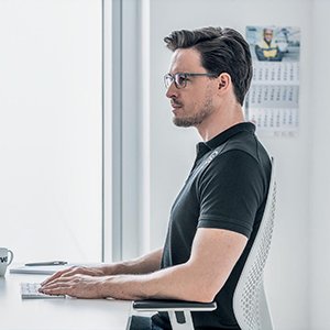 Man wearing computer glasses with uvex Nahcomfort lenses sitting upright in front of a computer desktop