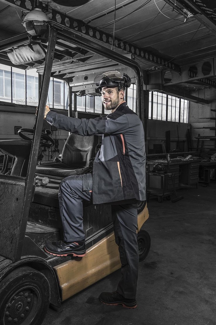 mężczyzna w osłonie twarzy wsiada do wózka widłowego