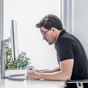 Man wearing standard glasses sitting hunched in front of a computer desktop