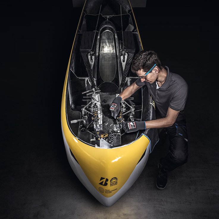 Mężczyzna w rękawicach ochronnych naprawia pojazd napędzany energią słoneczną