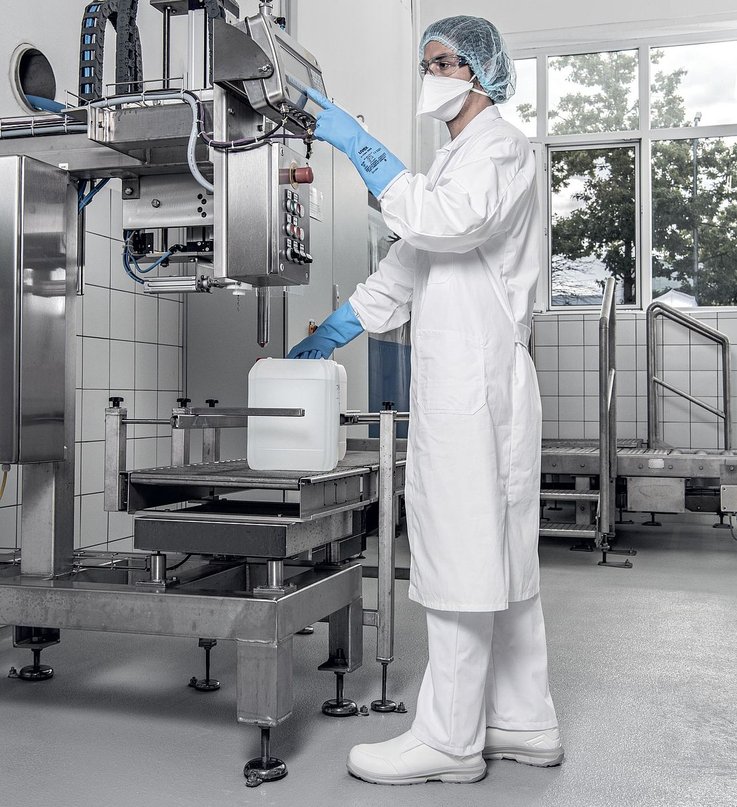 mężczyzna w fartuchu, półmasce, rękawicach i obuwiu ochronnym