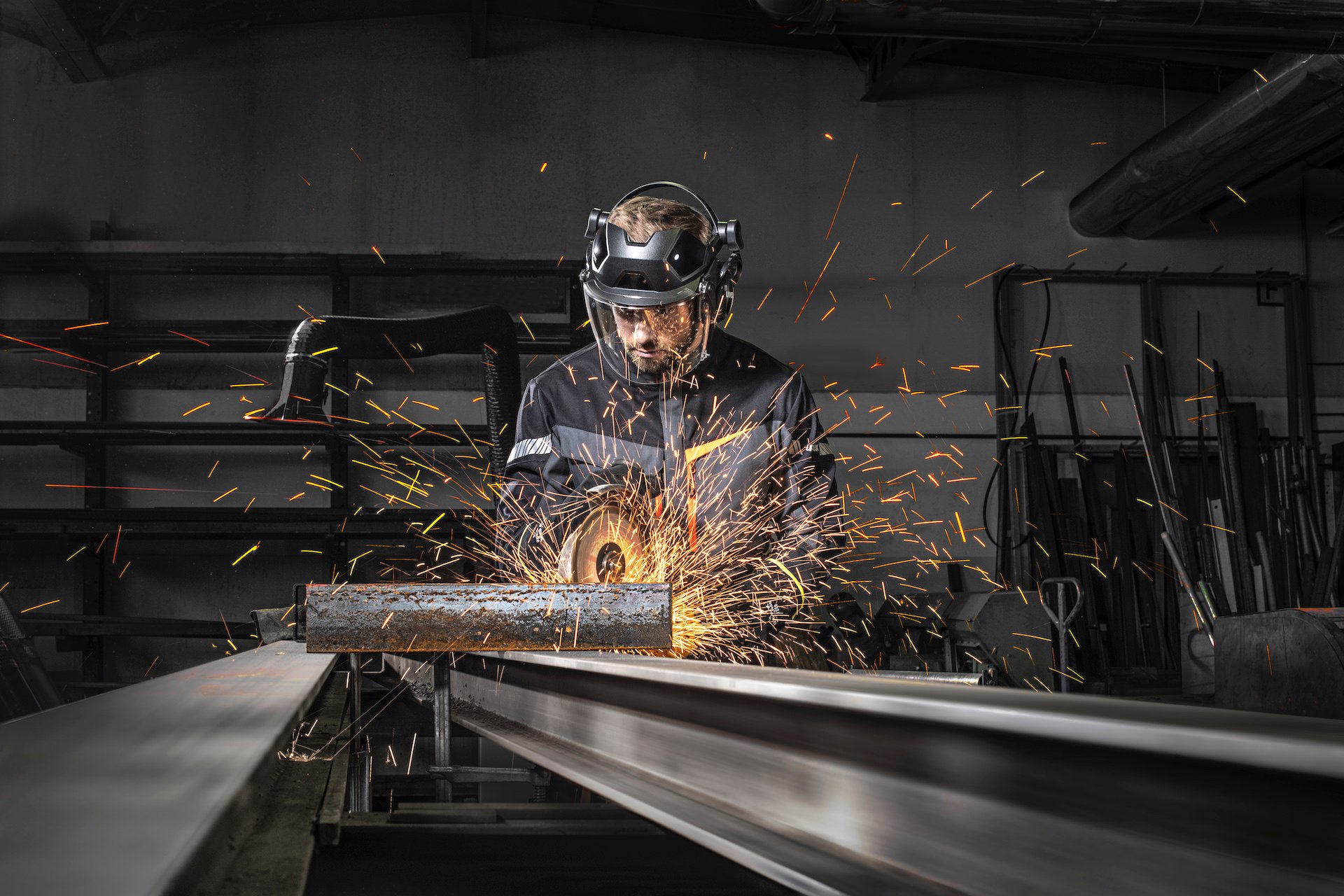 mężczyzna w osłonie twarzy tnie metalowe elementy