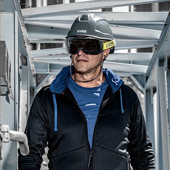 mężczyzna w szarym kasku na głowie i przeciwłonecznych goglach ochronnych patrzy w dal